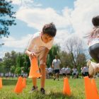 Children playing an obstacle course in a park on a sunny day, promoting fun and physical fitness.