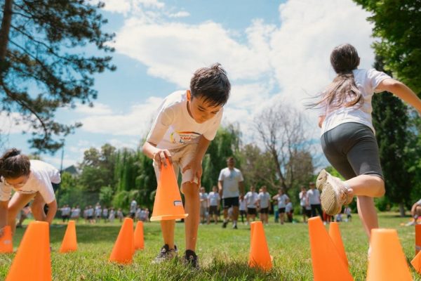 Children playing an obstacle course in a park on a sunny day, promoting fun and physical fitness.