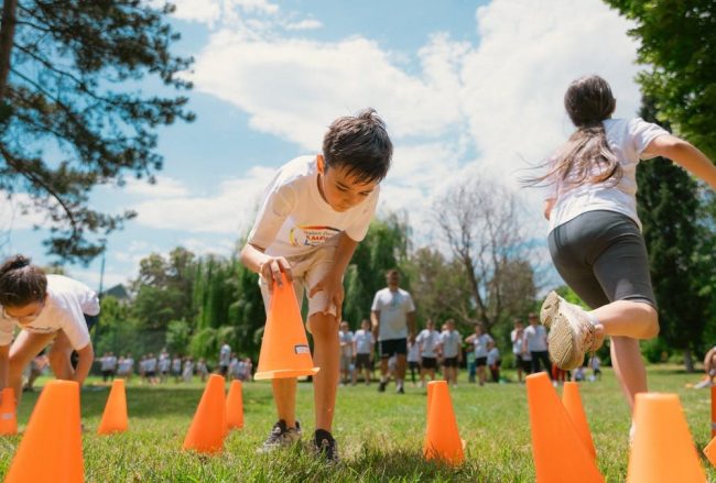 Children playing an obstacle course in a park on a sunny day, promoting fun and physical fitness.