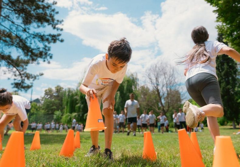 Children playing an obstacle course in a park on a sunny day, promoting fun and physical fitness.